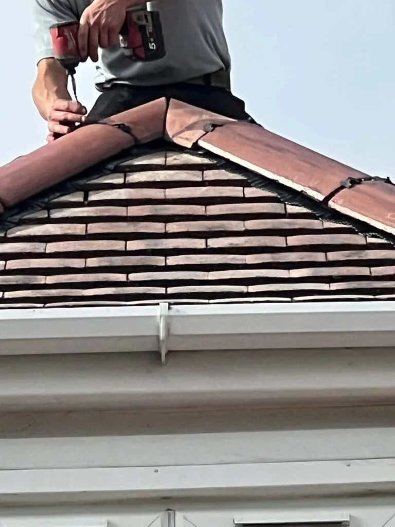 This is a photo of one of the operatives of MCM Roofing Repairs Wimborne installing new ridge tiles